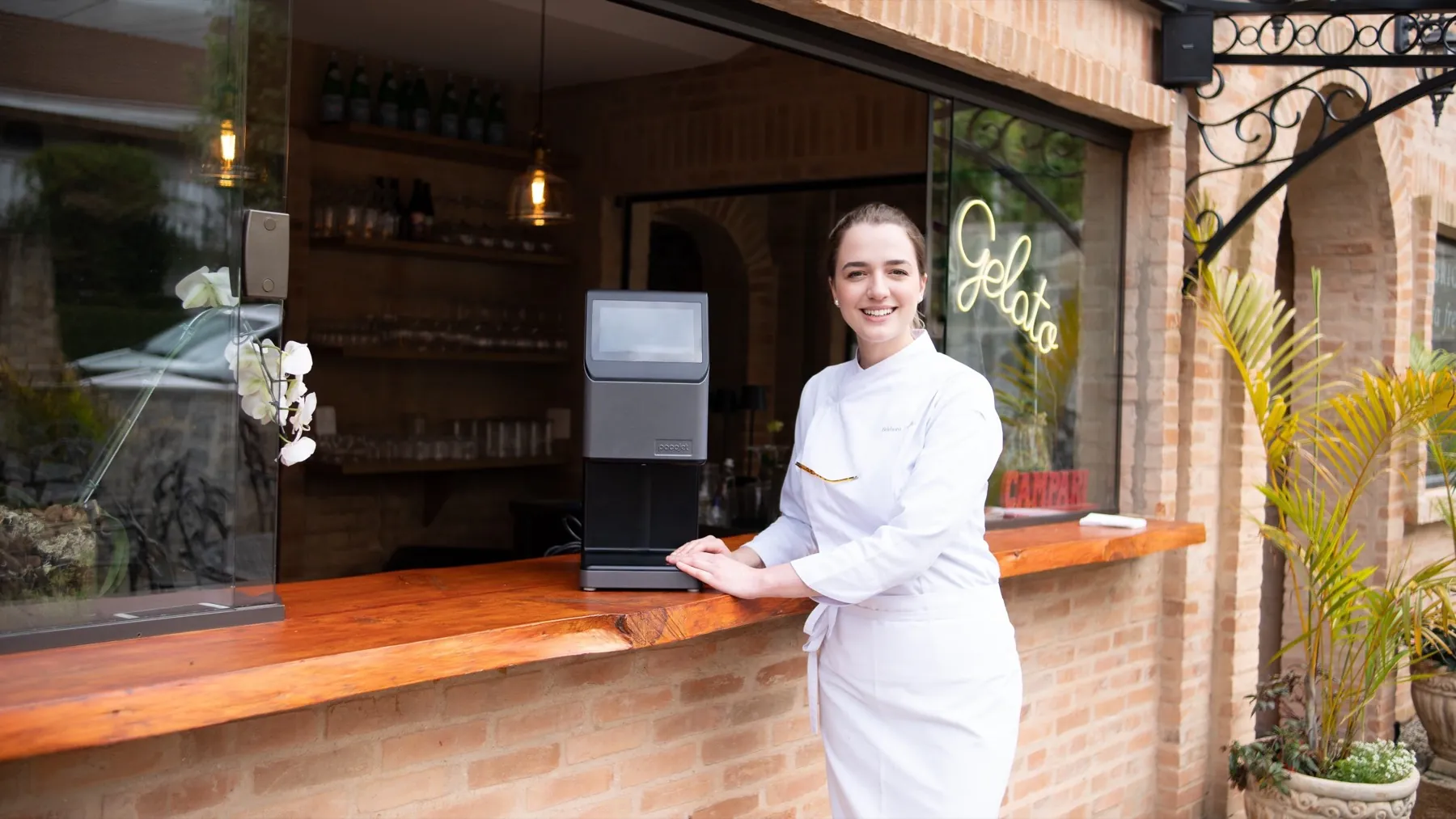 Chef Bárbara Cardin, embaixadora do Pacojet no Brasil, ao lado do balcão de uma gelateria com o Pacojet sobre a bancada