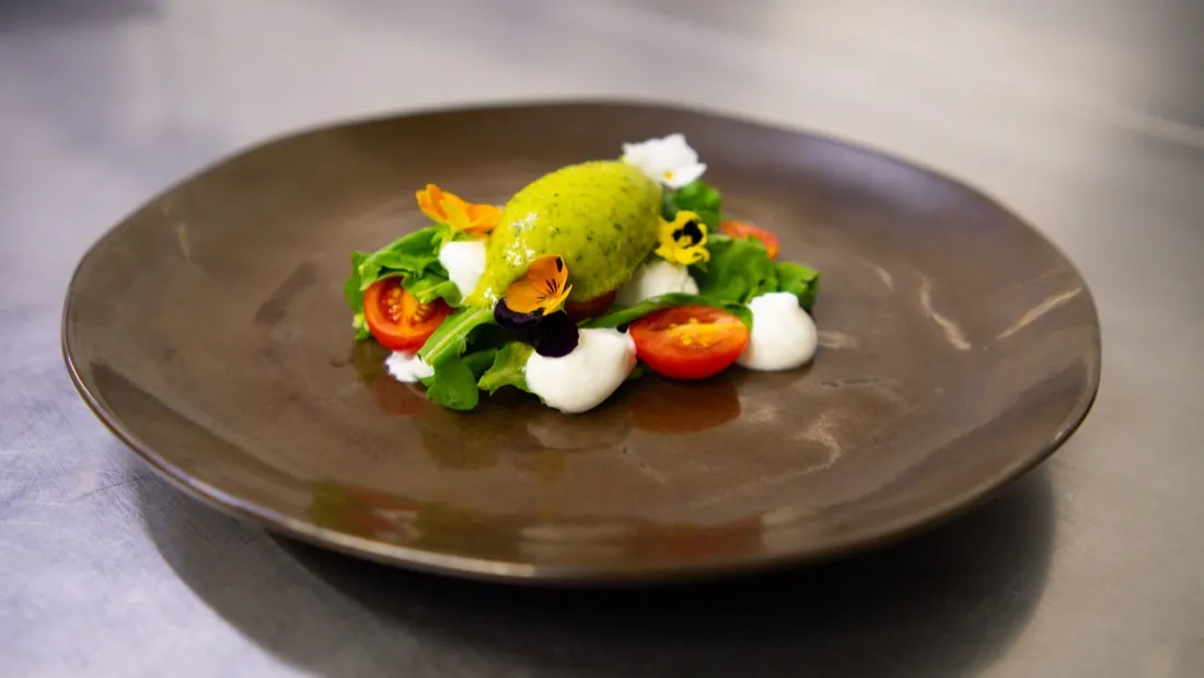 Quenelle verde pacotizada no Pacojet servida com tomates e flores comestíveis em prato de restaurante